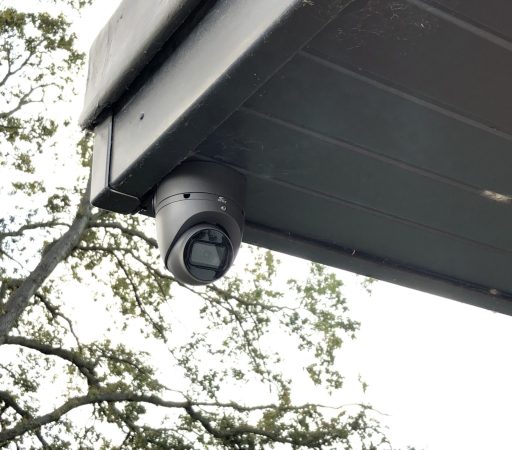 A security camera is mounted on the roof of a house.